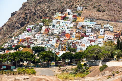 Colourful houses densely packed on a hillside in the Isla de San Andrés, creating a vibrant contrast against the rugged mountain backdrop.