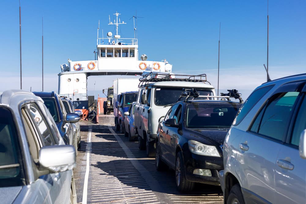 Autos in Reihen auf dem Deck einer Fähre, bereit für den Transport über ein Gewässer.