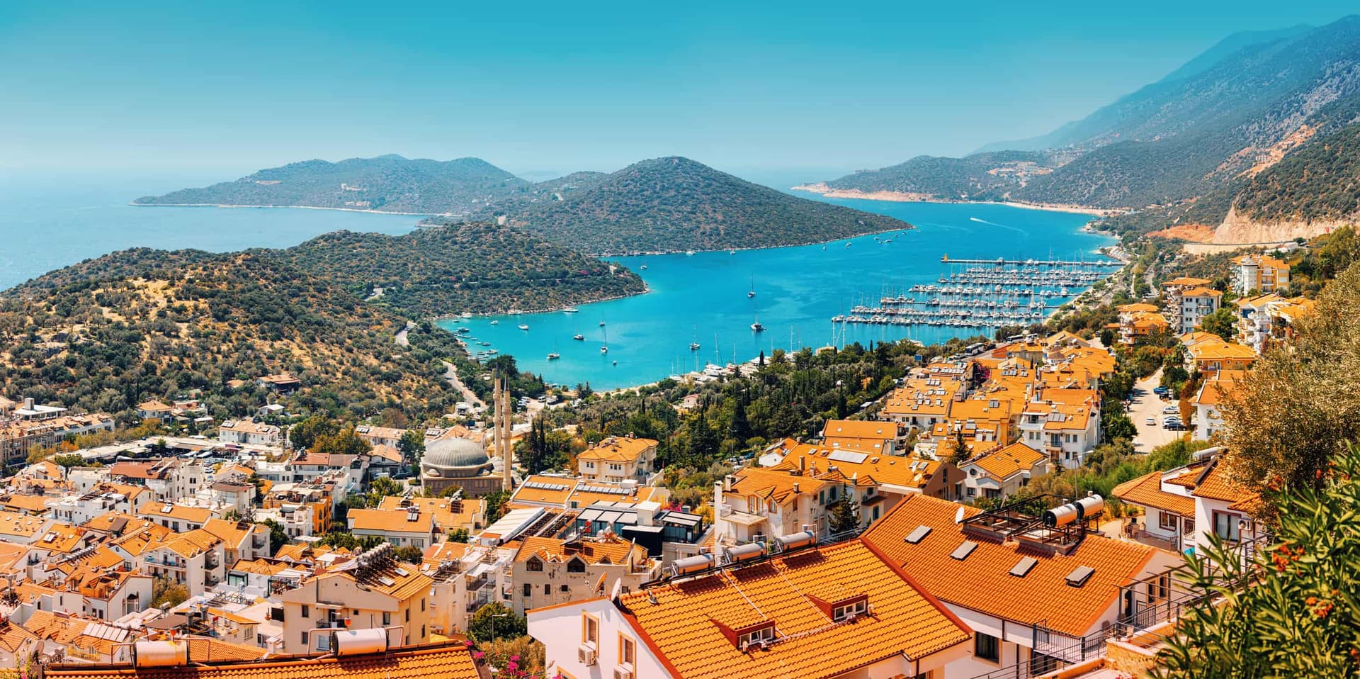 Blick auf die Stadt Kaş an der türkischen Mittelmeerküste mit rotdachigen Häusern und Yachthafen