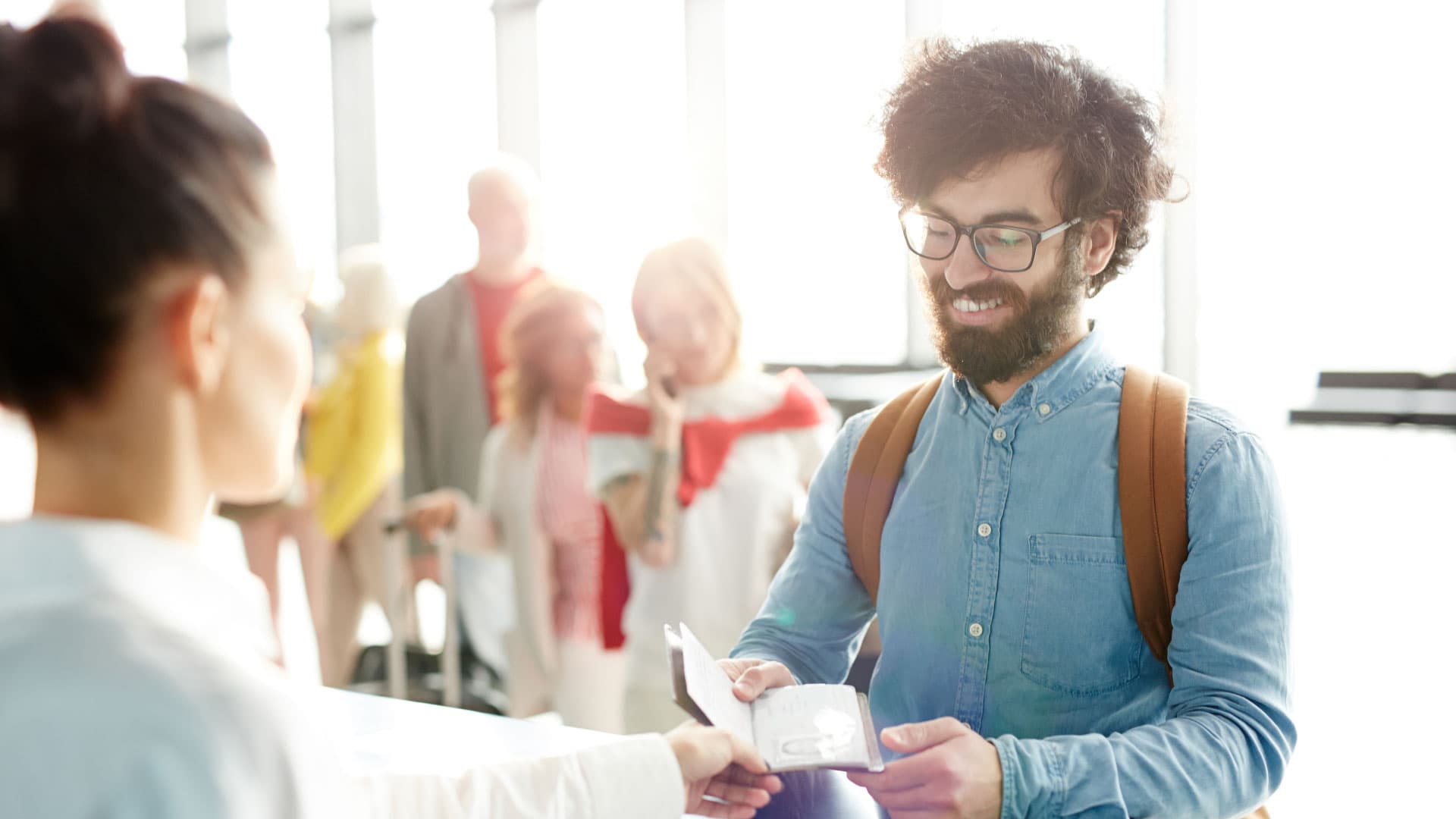A non-EU national hands his passport to a border control airport in a sunny airport.