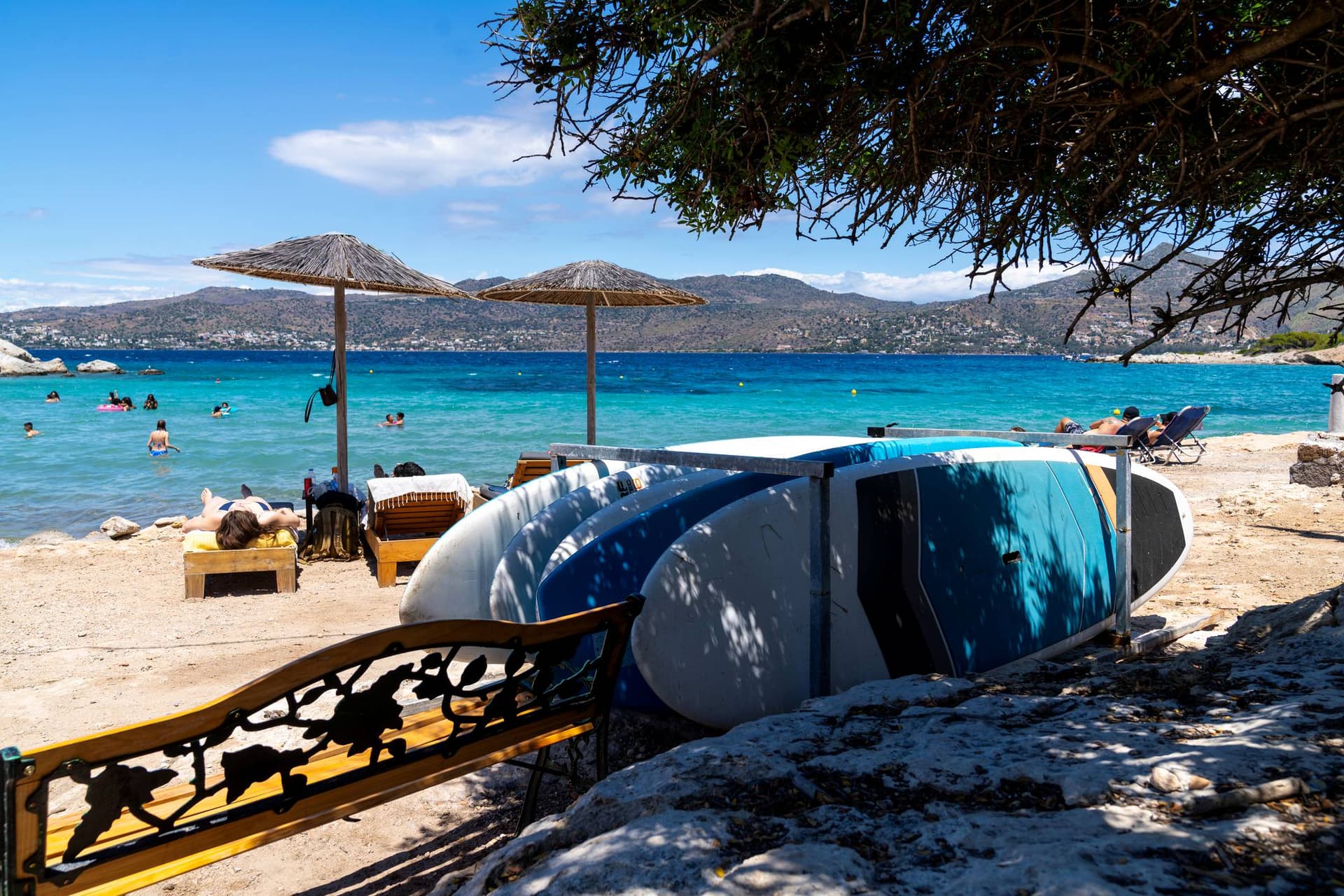 Paddleboards lie on a beautiful sandy beach in Aegina, Greece.