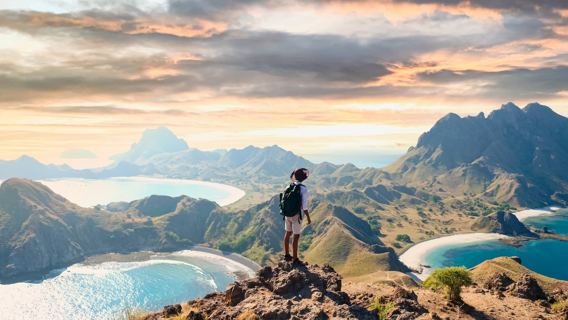 Man explores Padar Island hilltop with breathtaking mountain scenery and blue ocean, Komodo National Park, Indonesia.